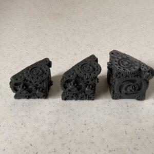 Three black 3D-printed mechanical parts on a white surface.