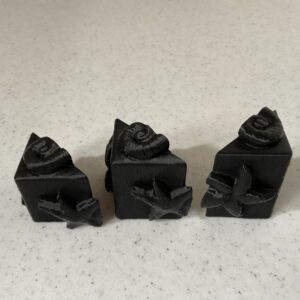 Three black LEGO minifigure heads with detailed faces and hats.