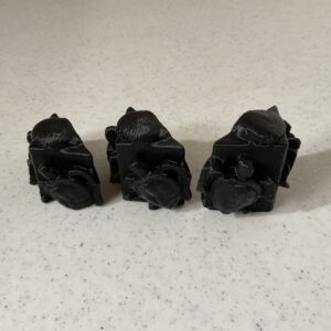 Three black, crumpled plastic objects on a white surface.