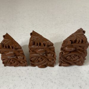 Three intricately carved brown wooden pieces with geometric designs.