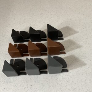 Nine pairs of plastic corner protectors in black, brown, and gray on a countertop.