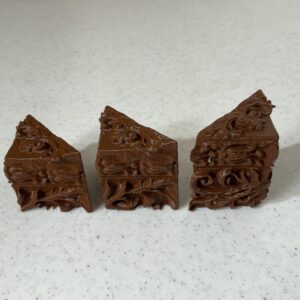 Three pieces of a chocolate dessert on a white surface.