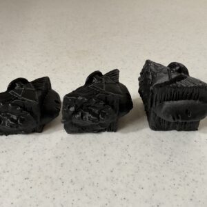 Three miniature black dragon figurines on a light surface.