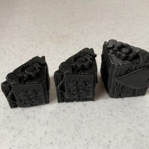 Three pieces of black charcoal or coal arranged on a white surface.