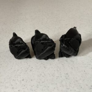 Three small black origami roses on a white surface.