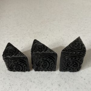 Three black decorative corner protectors with intricate patterns.