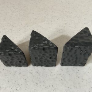 Three irregularly shaped black pumice stones on a light surface.