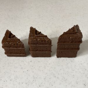Three pieces of chocolate with layered texture on a white surface.