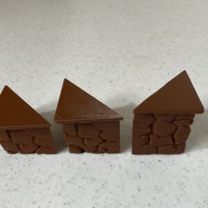 Three chocolate houses with triangular roofs on a white surface.