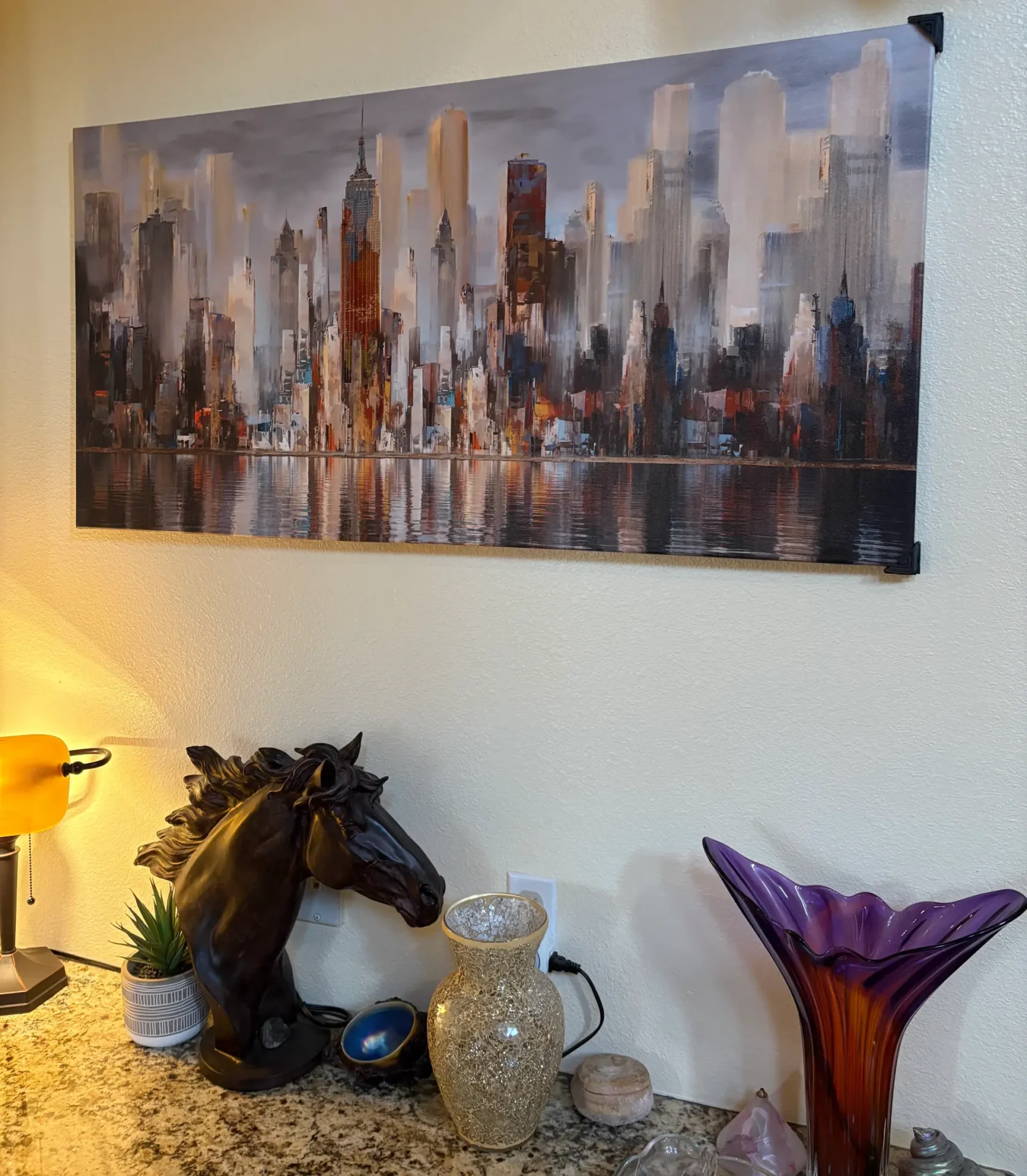 Cozy corner with decorative glass art and a cityscape painting above.
